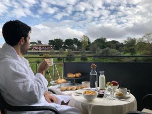 Un uomo seduto a un tavolo con una tazza di caffè di Unicum Roma Suites a Roma