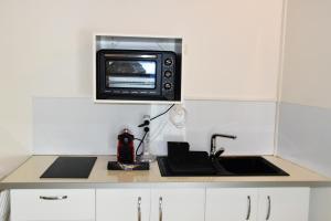 a kitchen with a sink and a microwave on a counter at Studio élégant à Baie Mahault de 19 m² avec balcon et parking in Baie-Mahault