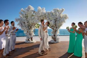 uma noiva e um noivo a beijarem-se em frente a uma festa de casamento em Secrets Bahia Mita Surf and Spa - All Inclusive - Adults Only em Punta Mita
