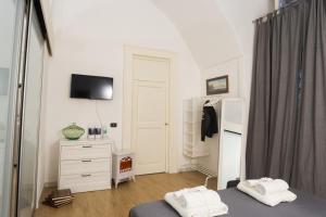 een slaapkamer met een bed, een ladekast en een televisie bij Residenza Sforza Apartment 2 in Napels