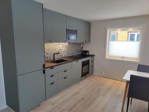 cocina con armarios grises y suelo de madera en Hurthi Apartment - Blue House, en Vardø 10 fotos más