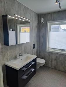 Un baño con lavabo, inodoro y espejo. en Hurthi Apartment - Blue House, en Vardø