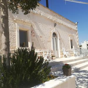 a small white building with chairs and a tree at Trulli Manuela 2 in Locorotondo