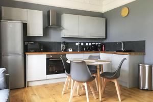 a kitchen with white cabinets and a table and chairs at Stylish 2 Bed Apart In The Heart of North Norfolk in North Walsham