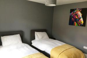 a bedroom with two beds and a painting on the wall at Stylish 2 Bed Apart In The Heart of North Norfolk in North Walsham