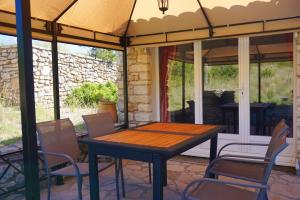 a wooden table and chairs on a patio at Maison de 2 chambres avec piscine partagee sauna et jardin amenage a Simiane la Rotonde in Simiane-la-Rotonde