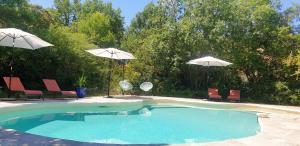 a swimming pool with two umbrellas and two chairs at Maison de 2 chambres avec piscine partagee sauna et jardin amenage a Simiane la Rotonde in Simiane-la-Rotonde