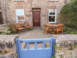 a blue fence in front of a house with a table and chairs at Rock House in Haverfordwest