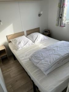 a bed with white sheets and pillows in a bedroom at Luxe stacaravan in Middelkerke