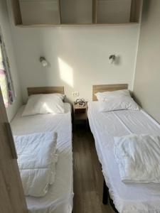 2 bedden in een kamer met witte lakens bij Luxe stacaravan in Middelkerke