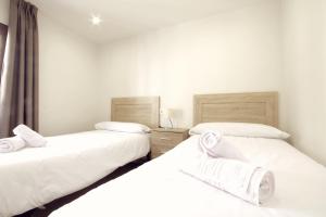 two twin beds in a room with white walls at Puerta de la Catedral in Toledo