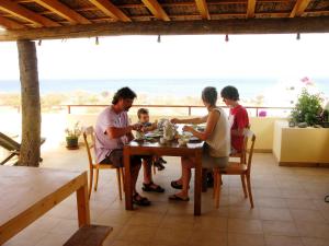 a family sitting at a table with the ocean in the background at Casa Strela B&B Tarrafal in Tarrafal