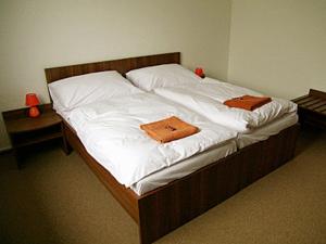 a bed with white sheets and orange towels on it at Penzión* ADONAI SLOVAKIA in Banská Bystrica