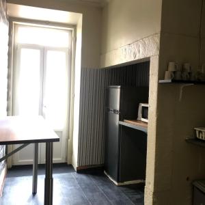 a kitchen with a refrigerator and a table and a window at Sri-Indo Guest House in Lisbon
