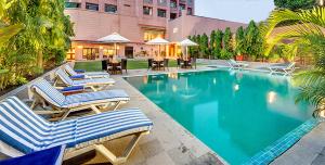 a swimming pool with lounge chairs and a hotel at Hotel Hindusthan International, Varanasi in Varanasi