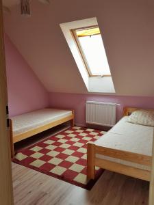 een zolderkamer met 2 bedden en een dakraam bij Przytulne mieszkanie w sercu Kaszub in Wąglikowice