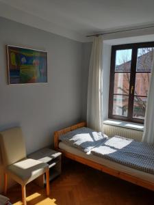 ein Schlafzimmer mit einem Bett, einem Stuhl und einem Fenster in der Unterkunft Ferienwohnung Madlene 2 in Gablitz