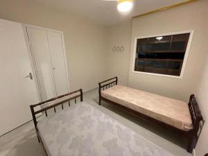 Duas camas num quarto com uma janela em Apartamento confortável na praça central em Águas de Lindoia