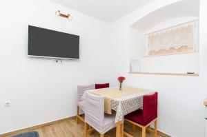 uma sala de jantar com uma mesa e uma televisão na parede em Apartment Ane em Split