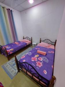 2 bedden in een kamer met paarse lakens bij Pink Homestay D'Perlis in Kangar