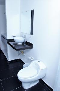 Eslait Hotel & Apartamentos في بارانكويلا: حمام به مرحاض أبيض ومغسلة
