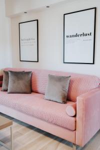 un sofá rosa en una sala de estar con dos cuadros en Sivota luxury collection en Sivota