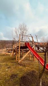 a playground with a red slide in a field at Casa cu Prispa in Sighişoara