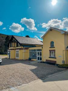 a yellow house with a car parked in the driveway at Glendalough International Youth Hostel in Laragh