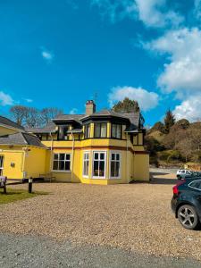 a yellow house with a car parked in front of it at Glendalough International Youth Hostel in Laragh