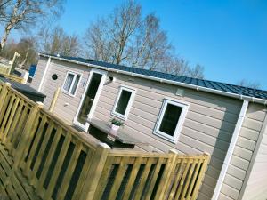una casa con una recinzione di legno di fronte ad essa di BJ Chalets - De Rug 1 - Vakantiepark Lauwersoog - LUXE chalet met vaatwasser! Vroege incheck! a Lauwersoog