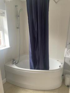 a bath tub with a shower curtain in a bathroom at The Moorings Hotel in Edmondsley