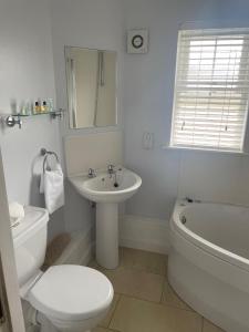 a white bathroom with a toilet and a sink at The Moorings Hotel in Edmondsley