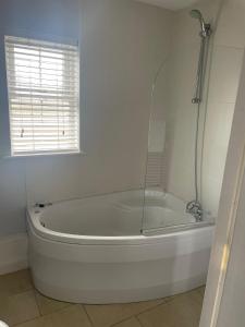 uma banheira branca na casa de banho com uma janela em The Moorings Hotel em Edmondsley