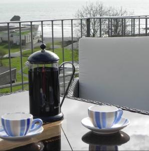 a tea kettle and two cups on a table at Bay View, Millendreth Looe Cornwall in Looe