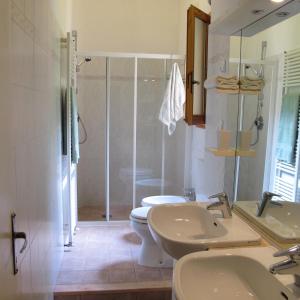 a bathroom with a toilet and two sinks and a shower at Casa Martellina - Holiday Home in Bagno a Ripoli