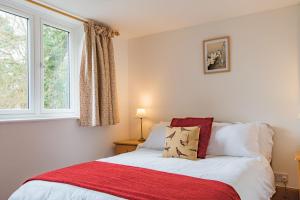 a bedroom with a bed with a red blanket and a window at Pheasants Lodge by Bloom Stays in Canterbury