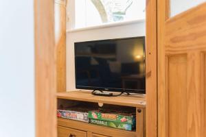 TV de pantalla plana en un centro de entretenimiento de madera en Pheasants Lodge by Bloom Stays, en Canterbury