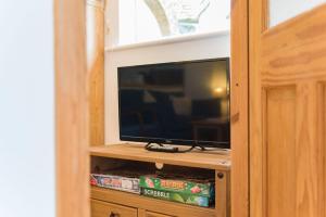 a flat screen tv sitting on a wooden entertainment center at Pheasants Lodge by Bloom Stays in Canterbury