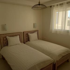 2 camas individuais num quarto com uma janela em Taghazout Océan with pool , fitness and ocean view em Taghazout