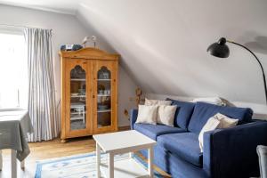ein Wohnzimmer mit einem blauen Sofa und einem Schrank in der Unterkunft Alt Wyk in Wyk auf Föhr