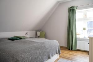 ein weißes Schlafzimmer mit einem Bett und einem Fenster in der Unterkunft Alt Wyk in Wyk auf Föhr