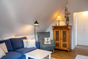 ein Wohnzimmer mit einem blauen Sofa und 2 Stühlen in der Unterkunft Alt Wyk in Wyk auf Föhr