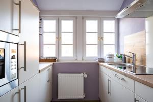 eine Küche mit weißen Schränken, einem Waschbecken und Fenstern in der Unterkunft Alt Wyk in Wyk auf Föhr