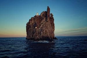 a large rock in the ocean with a cross on it at Via Marina in Stromboli