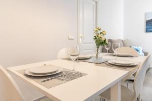 a white dining room table with plates and wine glasses at Apartamento con patio a 1 minuto de la playa in Fuengirola