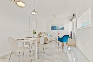 a white dining room with a white table and chairs at Apartamento con patio a 1 minuto de la playa in Fuengirola