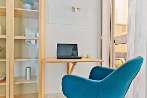 a blue chair sitting next to a desk with a laptop at Apartamento con patio a 1 minuto de la playa in Fuengirola
