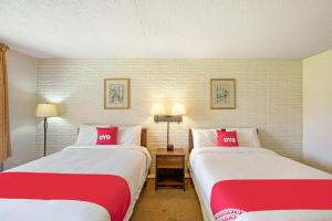 2 letti in camera con cuscini rossi e bianchi di OYO Hotel Doswell Kings Dominion a Doswell