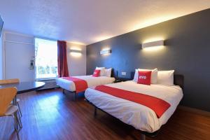 Cette chambre comprend 2 lits et une table. dans l'établissement OYO Hotel Valdosta GA I-75, à Valdosta
