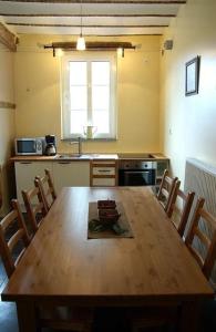 a kitchen with a wooden table with chairs and a window at Vakantiewoningen-Pizzeria Blanckthys Voeren in Voeren